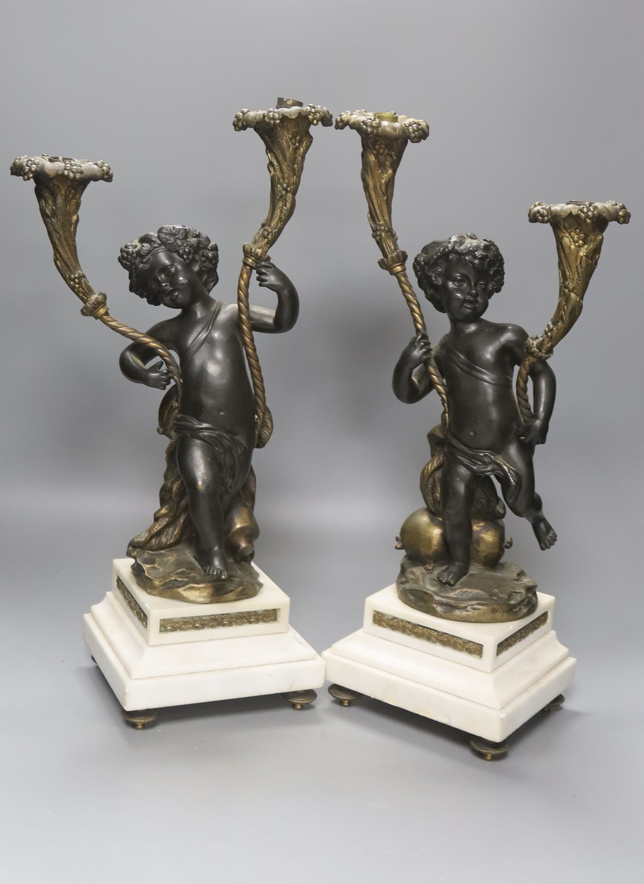 After Clodion. A pair of bronze cherub candelabra on marble bases, converted to lamps, height 42cm